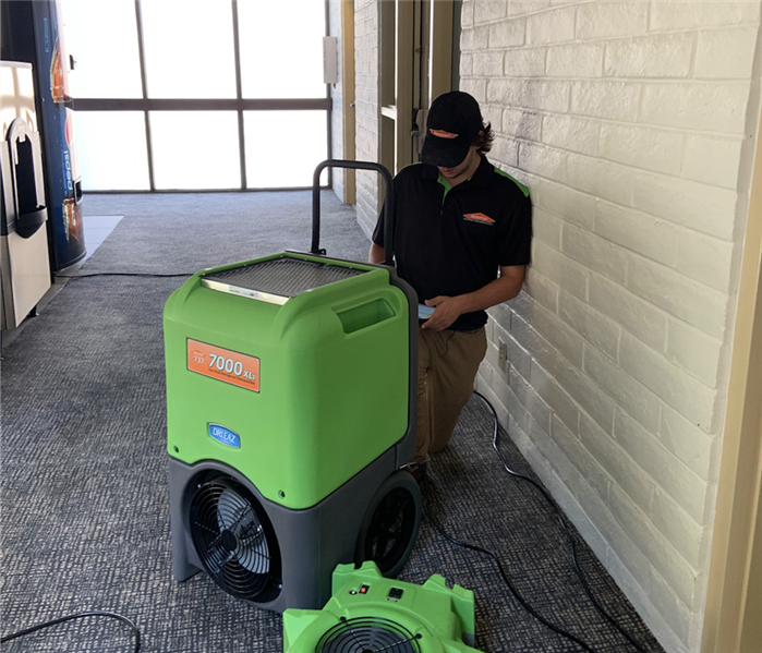Team member setting up a dehumidifier and air mover.